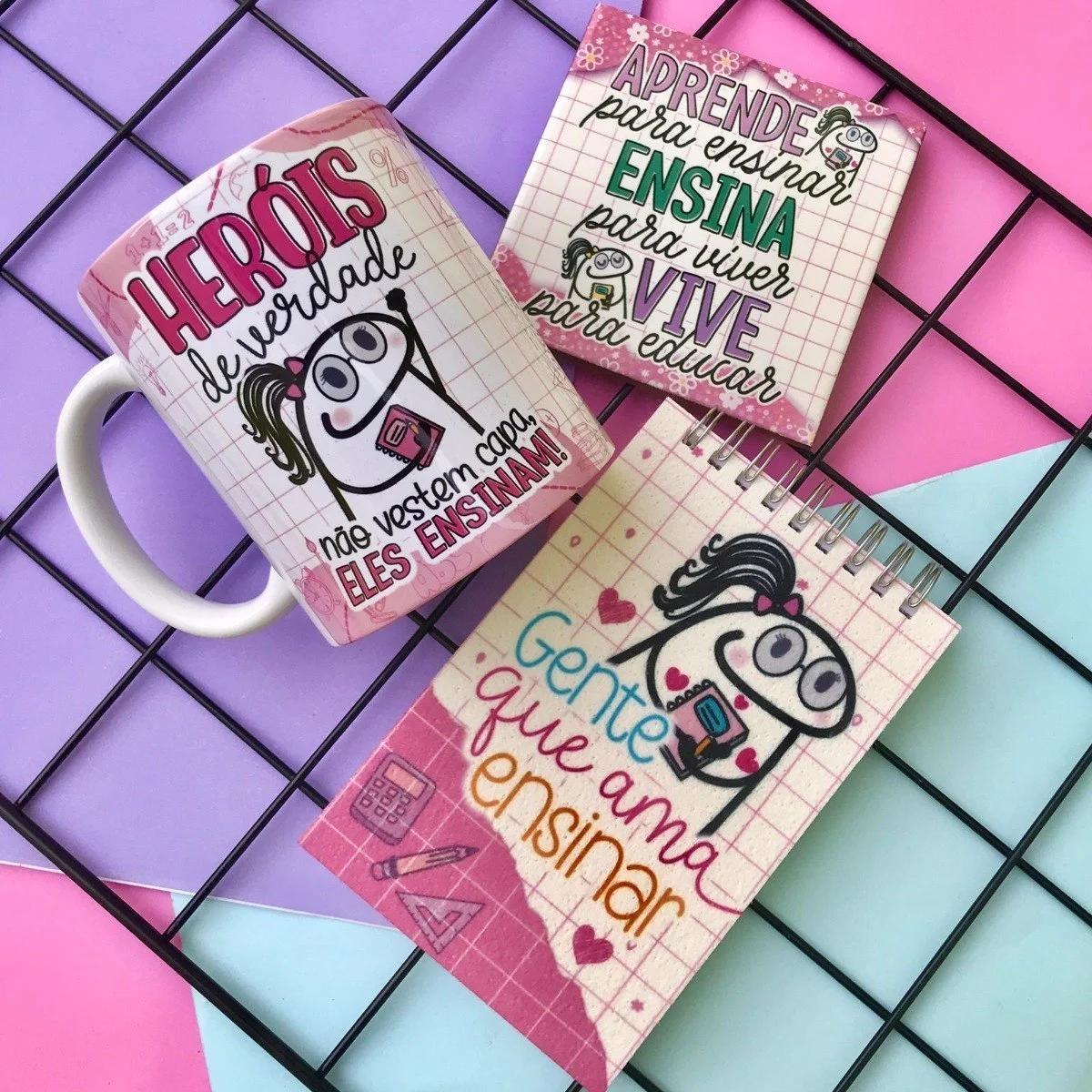 Caneca branca e dois blocos com estampas educacionais em fundo quadriculado e colorido.