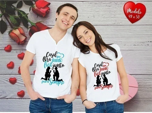 Casal sorridente vestindo camisetas brancas personalizadas com estampas e fundo de madeira.