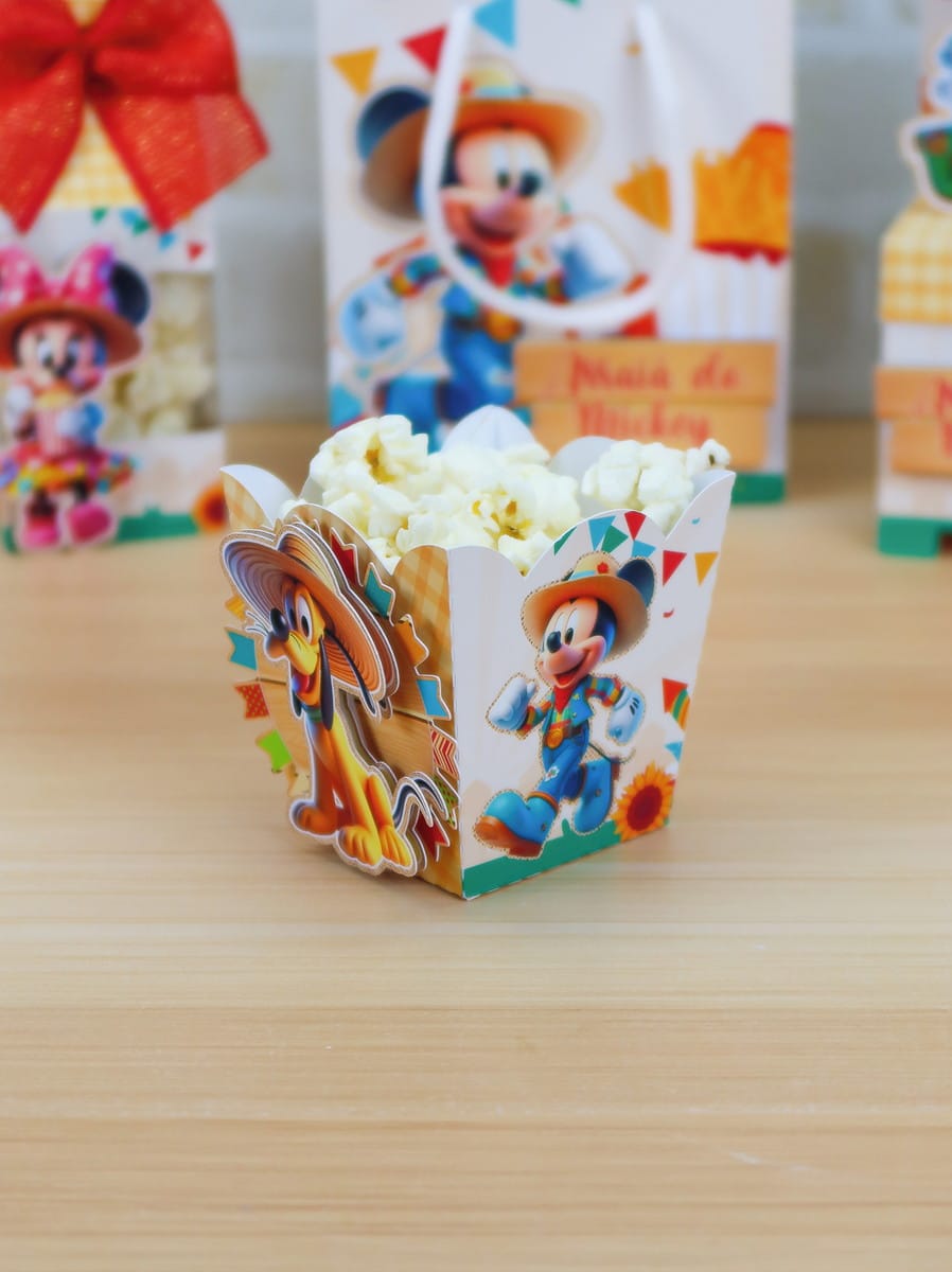 Arquivo de Corte Arraiá da Turma do Mickey Studio 2 Caixa de pipoca decorada com personagens de desenho animado sobre mesa de madeira.