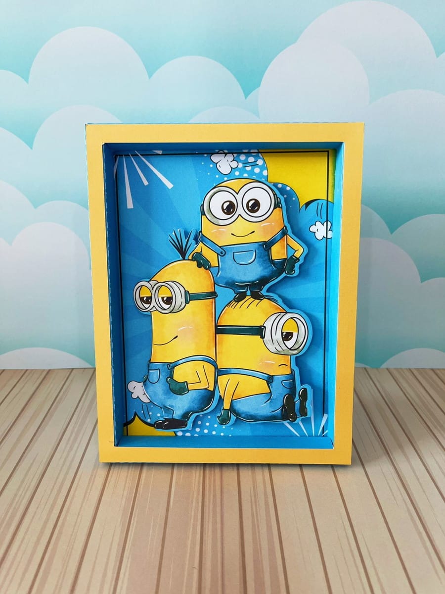 Arquivo de Corte Festa Minions Luxo em Studio e PDF 5 Três personagens amarelos de óculos em arte digital 3D com fundo azul e moldura amarela.