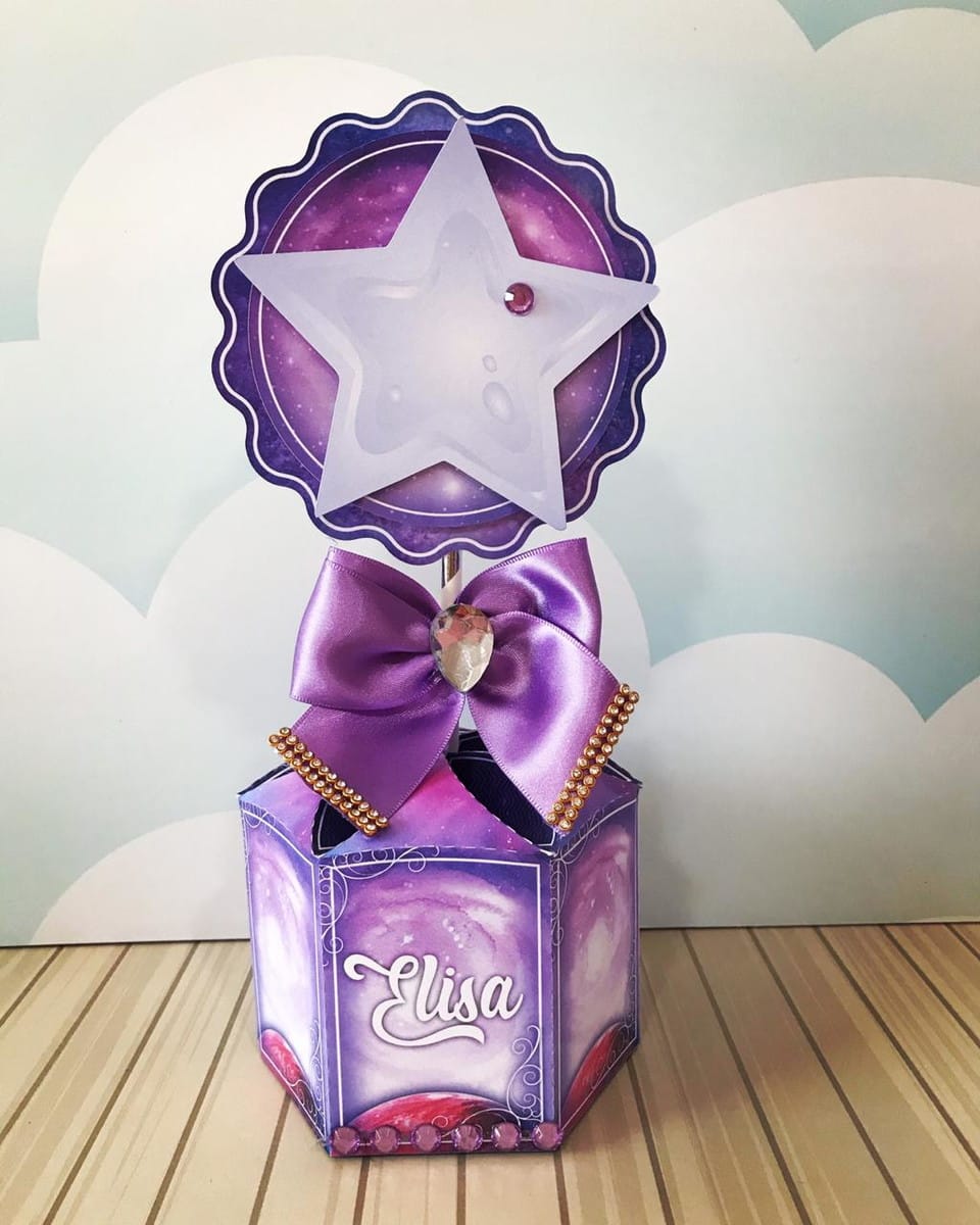 Arquivo de Corte Galáxia para Festa de 15 Anos 3 Design de centro de mesa roxo com estrela translúcida, laço de cetim e padrão de galáxia.
