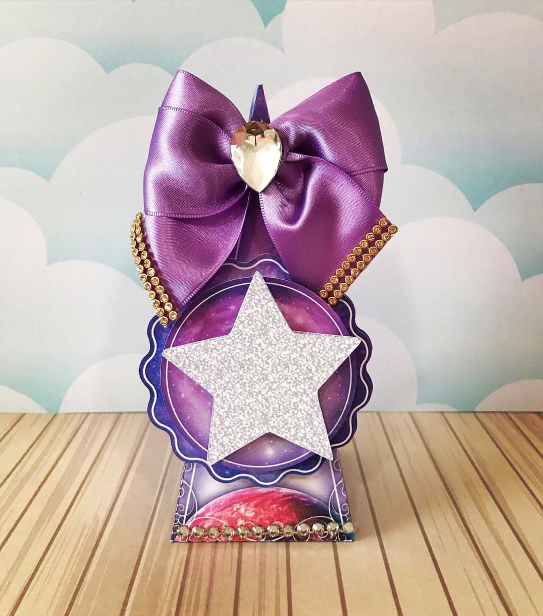 Arquivo de Corte Galáxia para Festa de 15 Anos 4 Caixa decorativa roxa com tema espacial, laço e estrela glitter prateada.