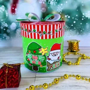 Caixa cilíndrica verde decorada com temas natalinos e laço de fita verde