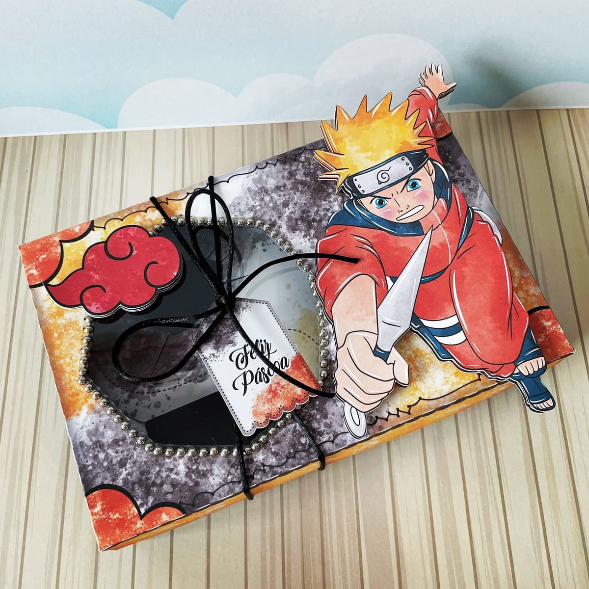 Caixa de Páscoa Naruto Kit Digital PDF PNG e Studio 2 Caixa decorada com personagem de anime, janela e tag "Feliz Páscoa".