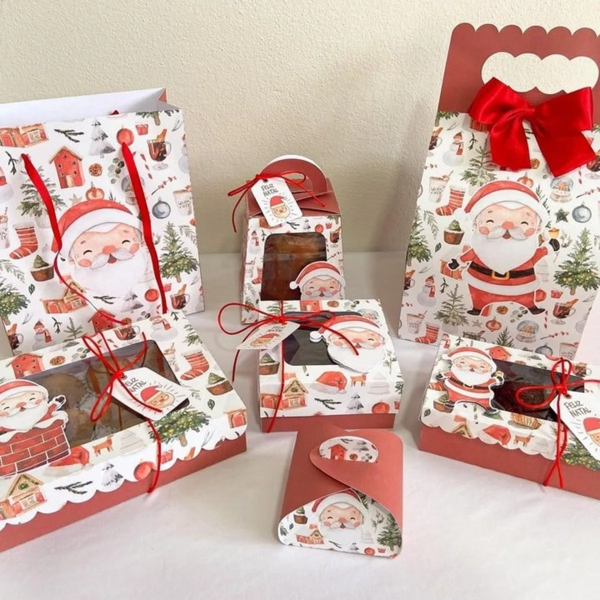 Embalagens de presente com tema natalino, incluindo sacolas e caixas decoradas com Papai Noel.