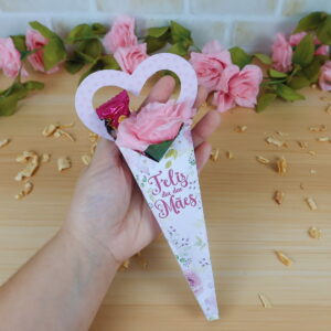 Mão segura cone de papel com rosa e chocolate para o Dia das Mães.