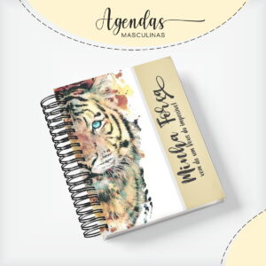 Agenda espiralada com capa de tigre aquarelado, olhos azuis vibrantes. Detalhe lateral com texto inspirador.