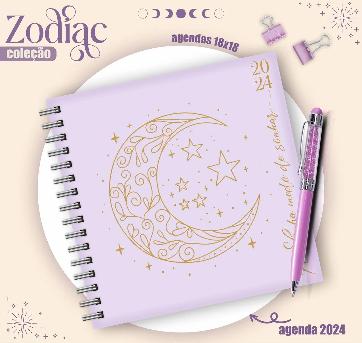 Agenda roxa espiralada com estampa dourada de lua e estrelas e caneta.