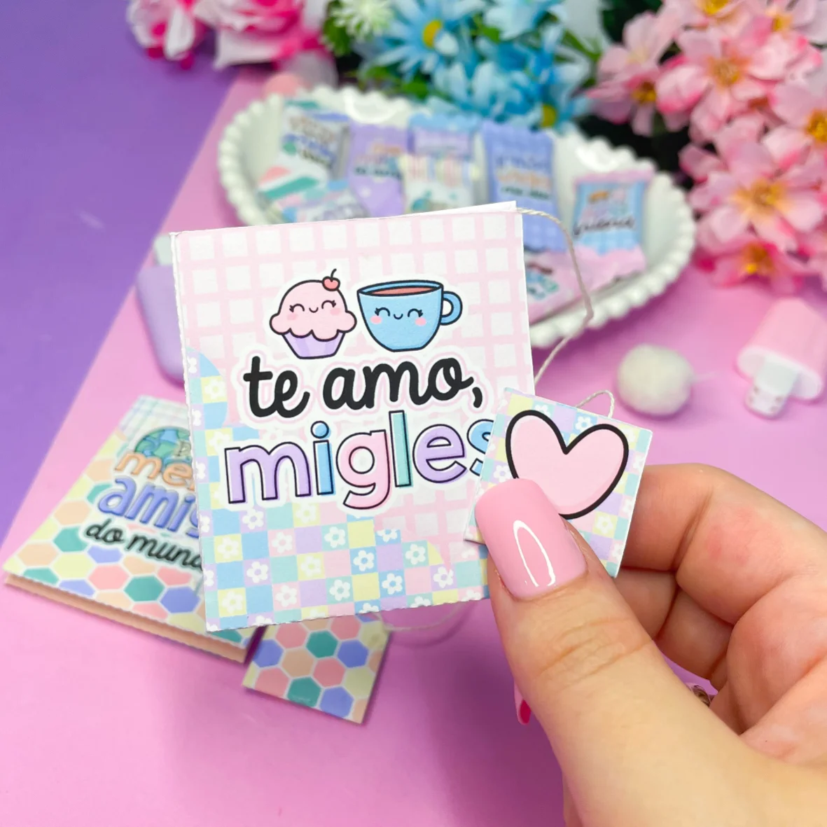 Mão com unha rosa segura tag de papel com desenhos fofos.