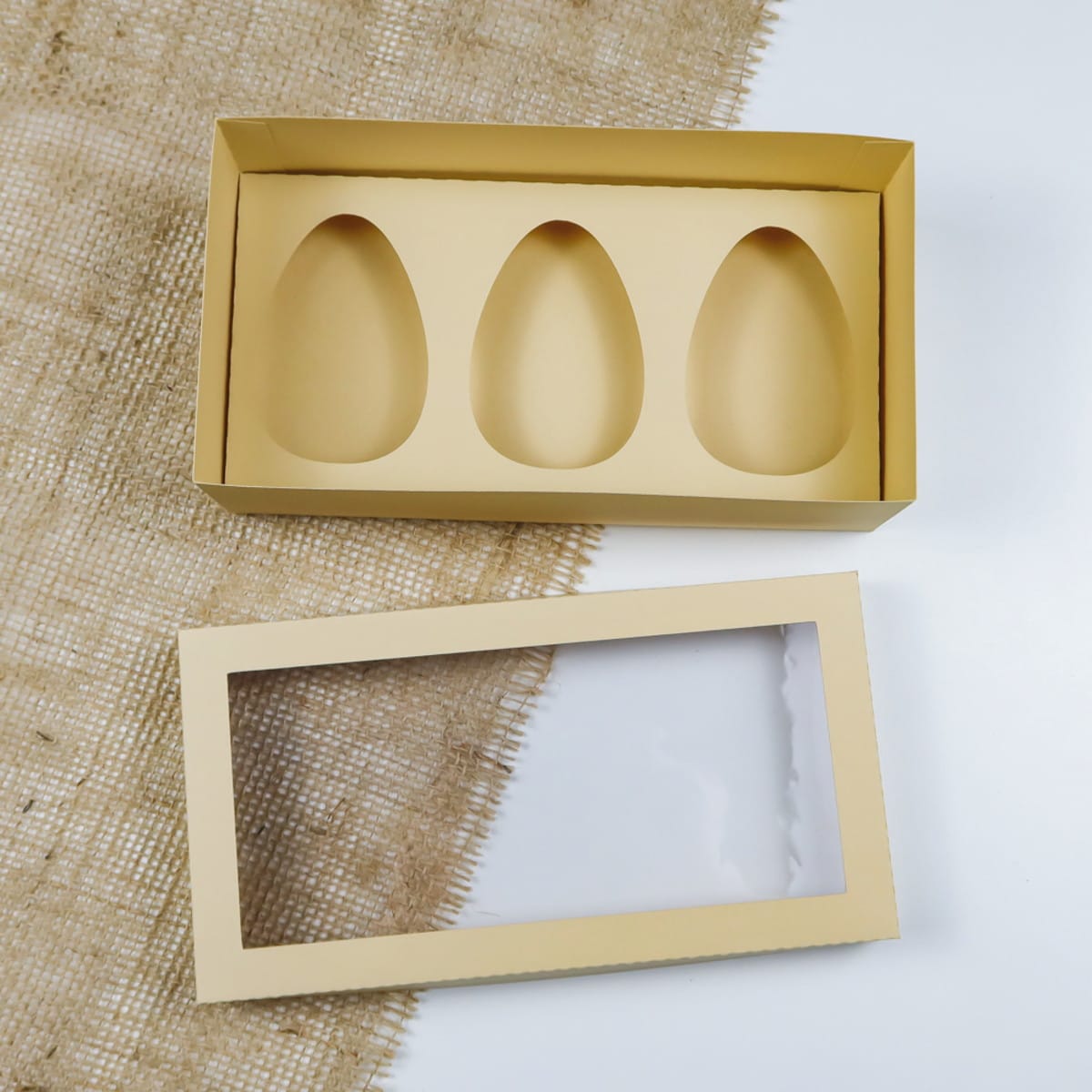 Kit Caixas de Páscoa com Moldes para Ovos e Doces Digital 4 Caixa de papelão vazia em formato retangular com três cavidades ovais para doces.