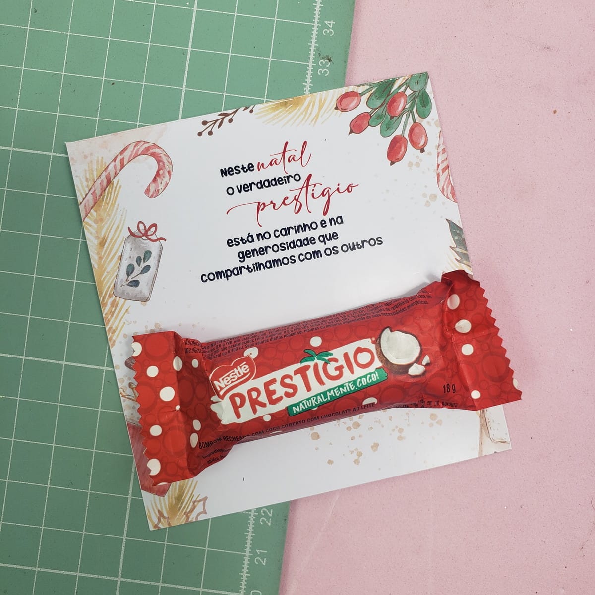 Kit Cards Doces Natal PNG para Lembrancinhas 2 Barra de chocolate em embalagem vermelha sobre cartão de Natal decorado em mesa.