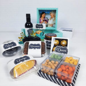 Cesta de presentes com vinho, queijo, brownie, geleia e doces variados.