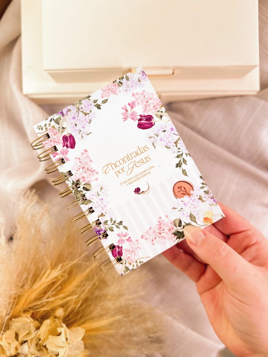 Kit Digital Dia da Mulher Cristão para Personalizados 3 Mão segura caderno espiral decorado com estampa floral rosa e lilás.