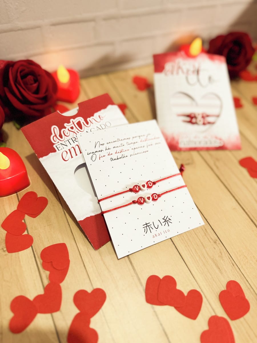 Kit Digital Dia dos Namorados com Mimos para Imprimir 2 Duas pulseiras de fio vermelho com miçangas em cartões, rodeadas por corações e rosas.
