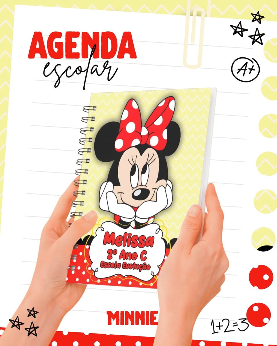 Kit Digital Escolar Minnie Mouse com Tabuada e Etiquetas 3 Duas mãos segurando uma agenda escolar com capa temática infantil colorida.