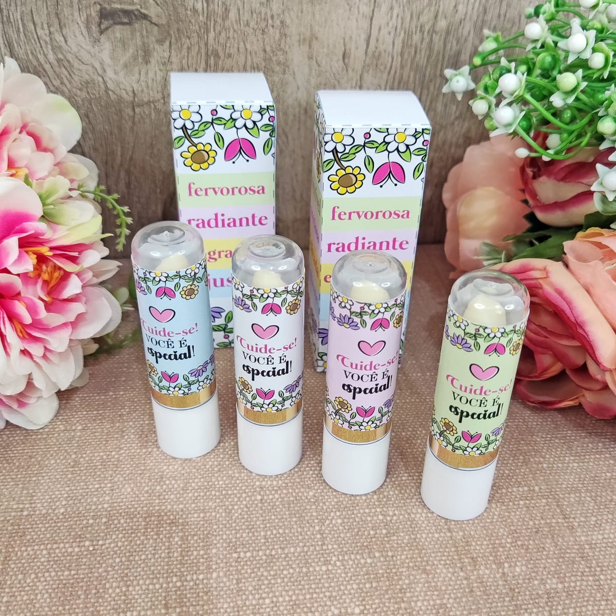 Kit Digital Dia da Mulher com PNG para Lembrancinhas 4 Quatro bastões de produto para lábios e duas caixas com embalagens florais coloridas.