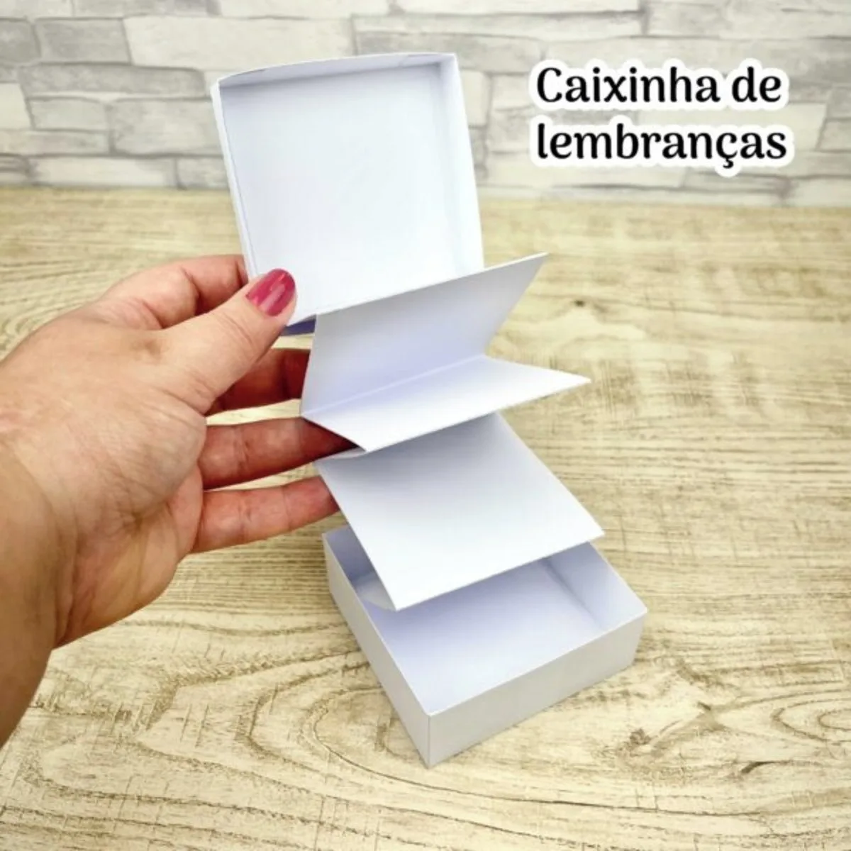 Mão segurando uma pequena caixa branca com sanfona de papel no interior aberto.