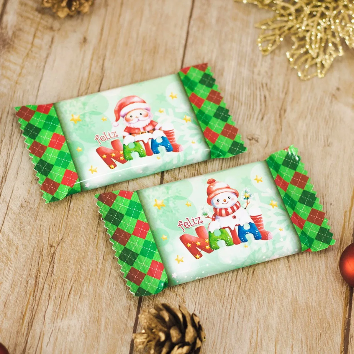 Dois chocolates embalados com tema natalino sobre uma mesa de madeira.