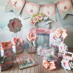Decorações de festa com design floral e borboletas, em tons pastel.