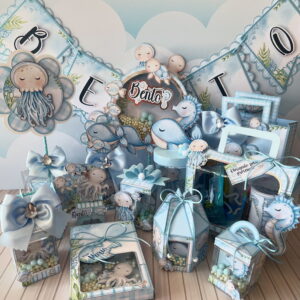 Decoração de festa infantil com tema marinho, caixas e baleias em tons azuis.