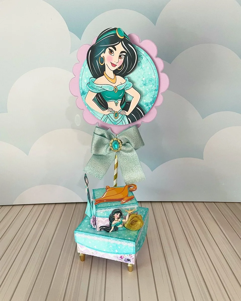 Topo de bolo com personagem de cabelo preto e vestido verde em fundo azul