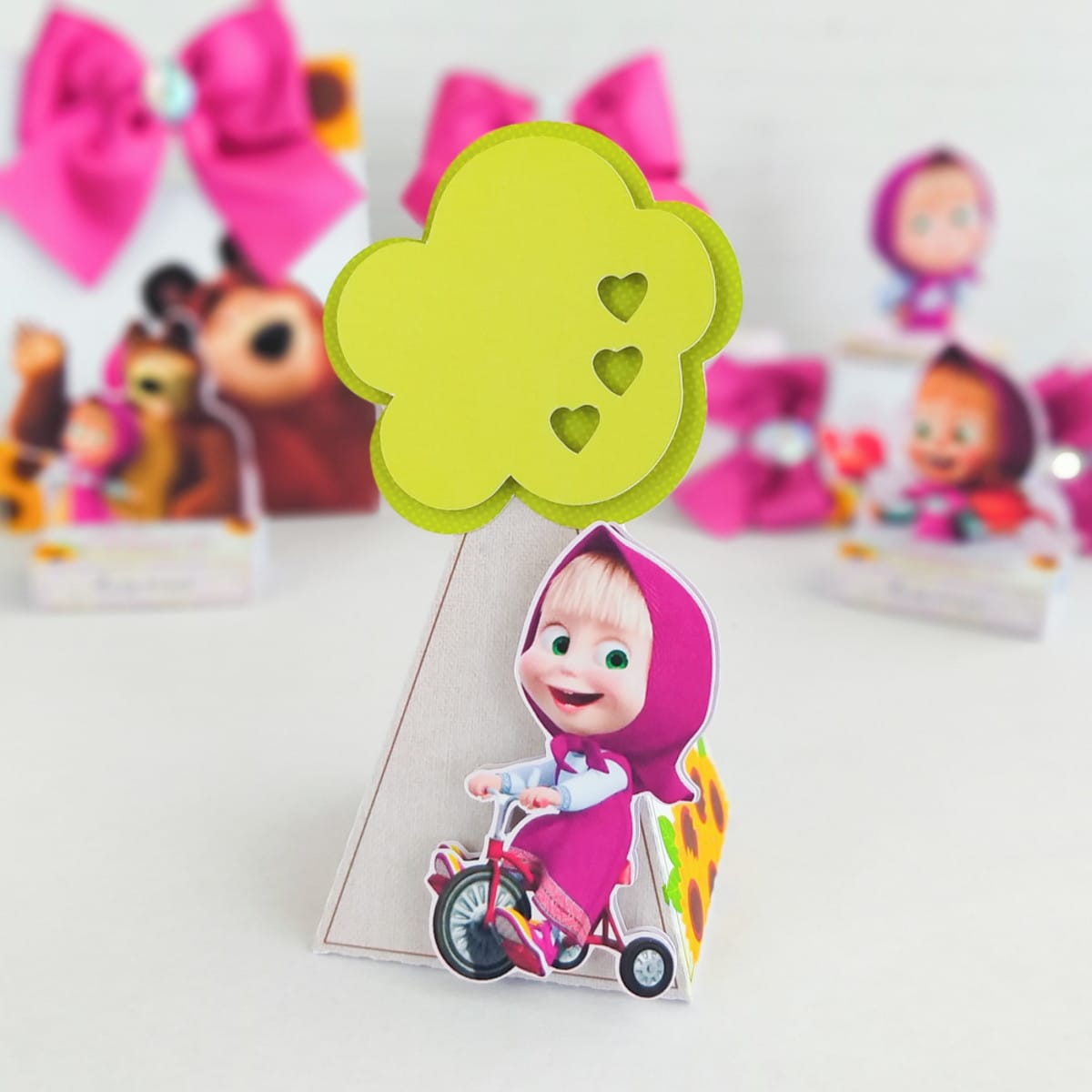 Kit Digital Completo Marsha e o Urso em PDF e Studio 2 Decoração de festa infantil com cone, menina de capuz rosa em bicicleta e nuvem verde com corações.