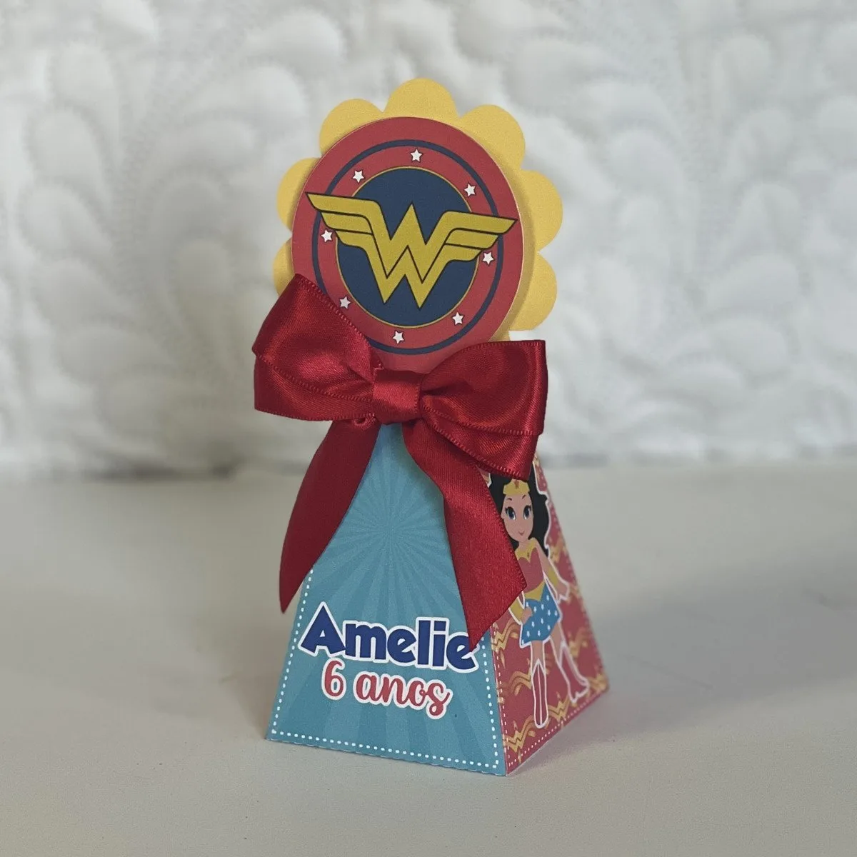 Caixa personalizada em formato cônico com laço vermelho e tema heroico.