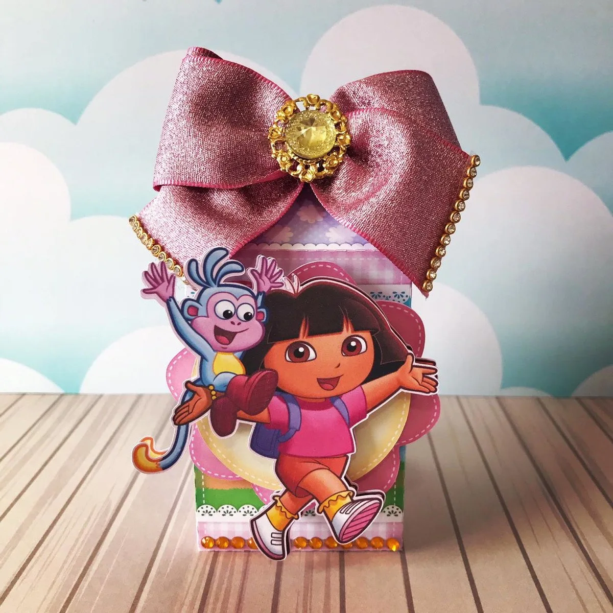 Caixa decorada de papel com laço rosa brilhante e personagens animados na frente.