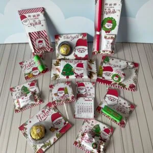 Vários itens de papelaria personalizada com tema de Natal sobre fundo de madeira branca.