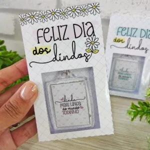 Mão segurando cartão decorado com margaridas contendo texto em português e chaveiro personalizado.