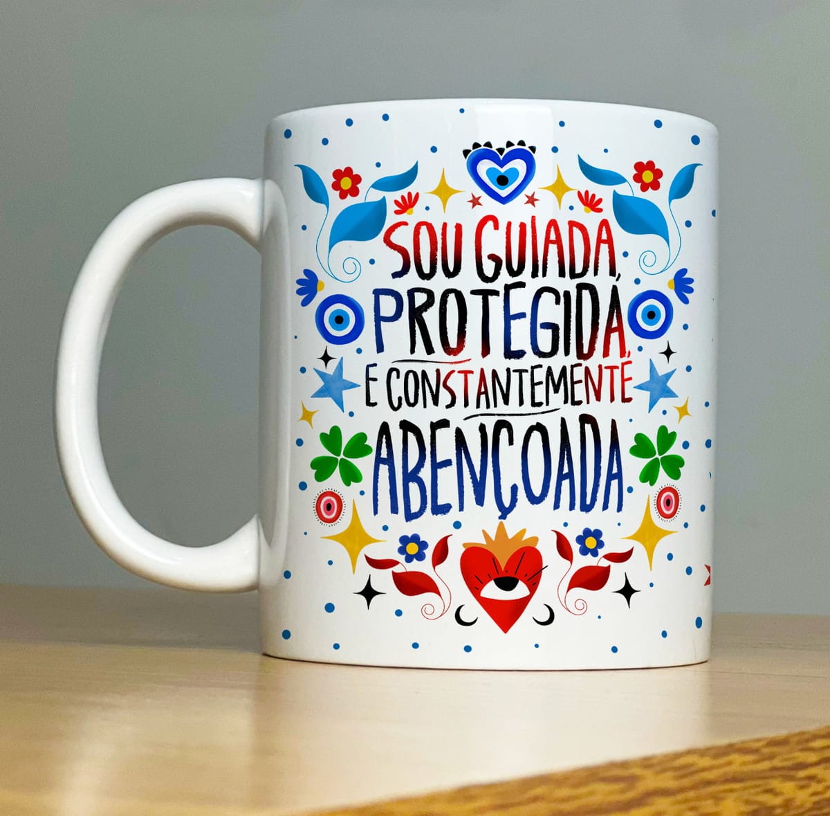 Kit Sublimação Caneca Proteção com 32 Artes em PNG 4 Caneca branca estampada com frase colorida e desenhos variados em fundo cinza.