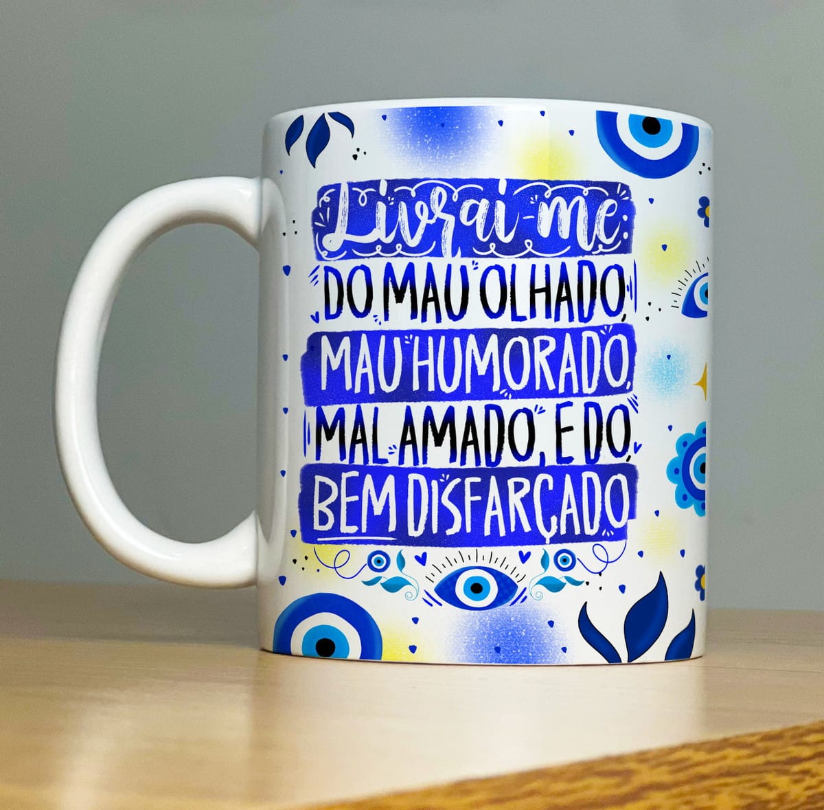 Kit Sublimação Caneca Proteção com 32 Artes em PNG 1 Caneca branca estampada com frases em azul e desenhos de olhos gregos.