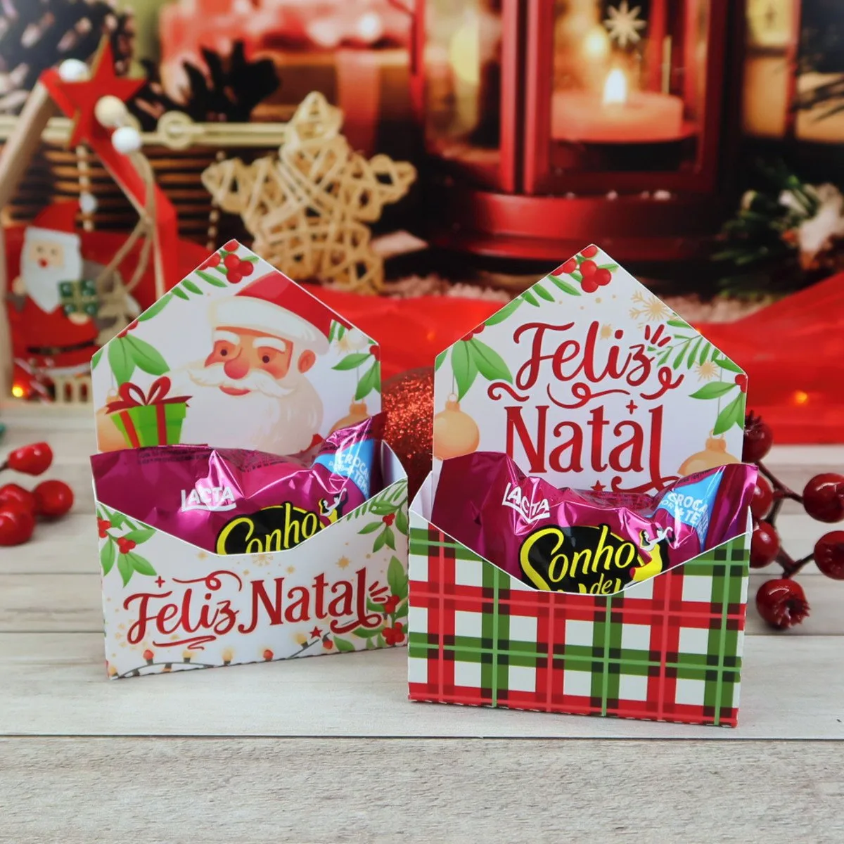 Duas caixinhas de papel com doces e ilustrações de Natal em fundo temático.