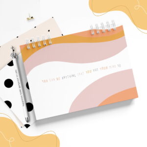 Caderno espiral com capa inspiradora e frase motivacional, caneta decorada.