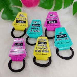 Porta Xuxinha Dia das Mães - Arquivo Digital 16 Seis cartões coloridos com frases em português e elásticos pretos para cabelo.